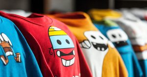 Row of colorful graphic t-shirts hanging with bright cartoon character designs showing well-maintained prints that demonstrate effective care techniques to prevent cracking