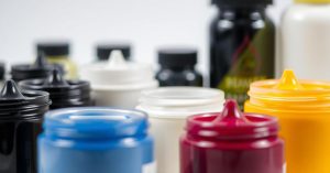 Various t-shirt printing inks in jars including plastisol, water-based, and specialty inks used for screen printing on fabric