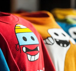 Row of colorful graphic t-shirts hanging with bright cartoon character designs showing well-maintained prints that demonstrate effective care techniques to prevent cracking
