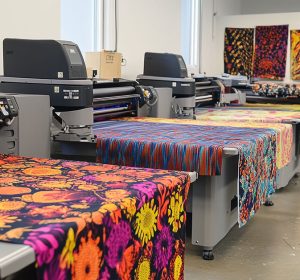 Large-scale DTF printing facility with multiple printers producing colorful fabric prints, showcasing direct to film printing pros and cons