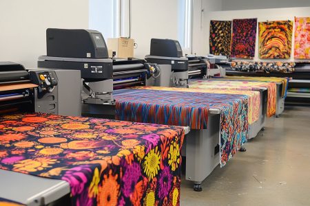 Large-scale DTF printing facility with multiple printers producing colorful fabric prints, showcasing direct to film printing pros and cons