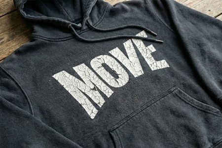 Black hoodie with severely cracked white print showing extensive cracking and peeling across printed letters on chest area